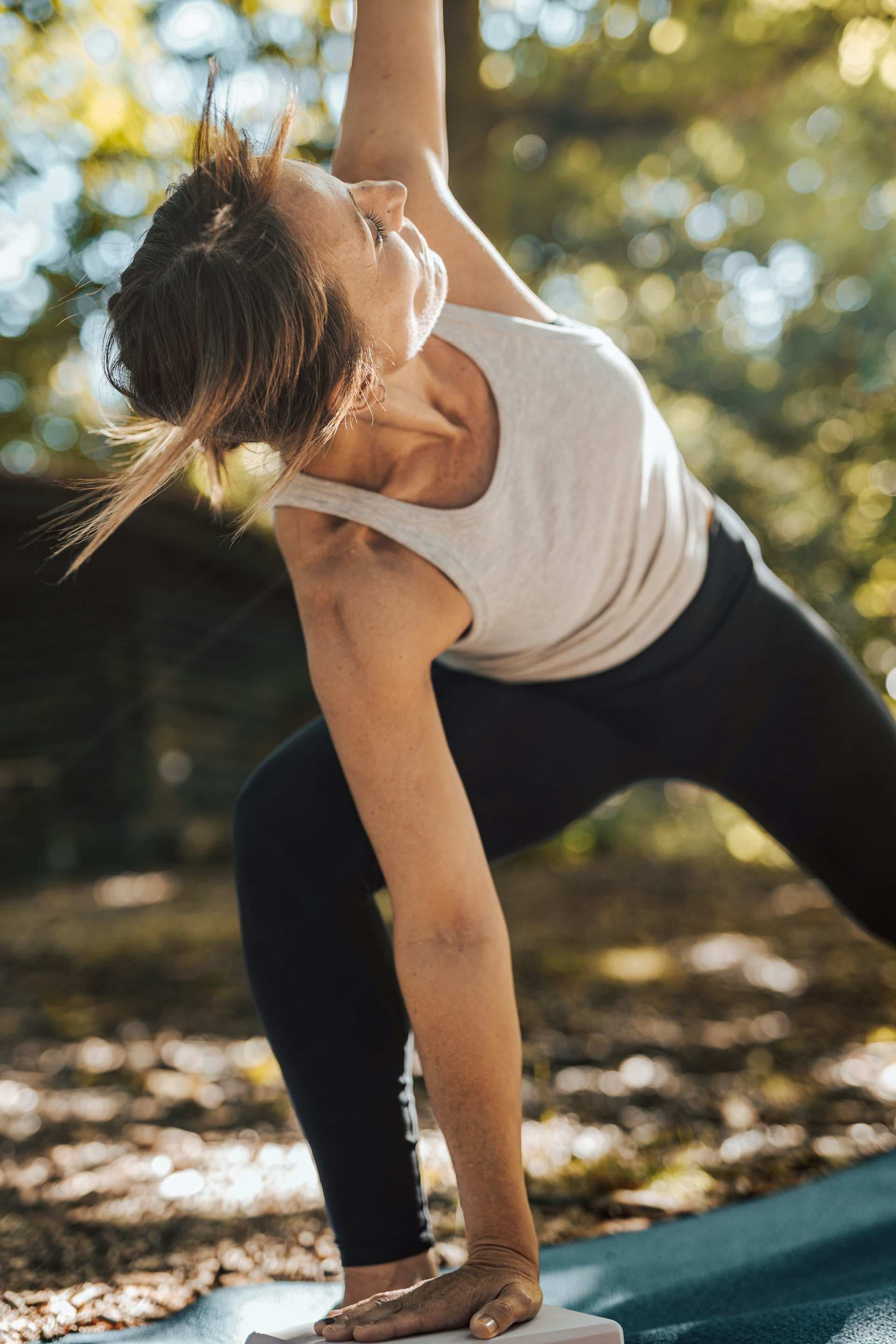 Eine Frau macht in der Natur Yoga und stützt sich auf dem Boden ab